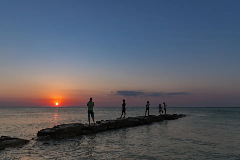 Personas viendo el atardecer sobre el mar en Holbox